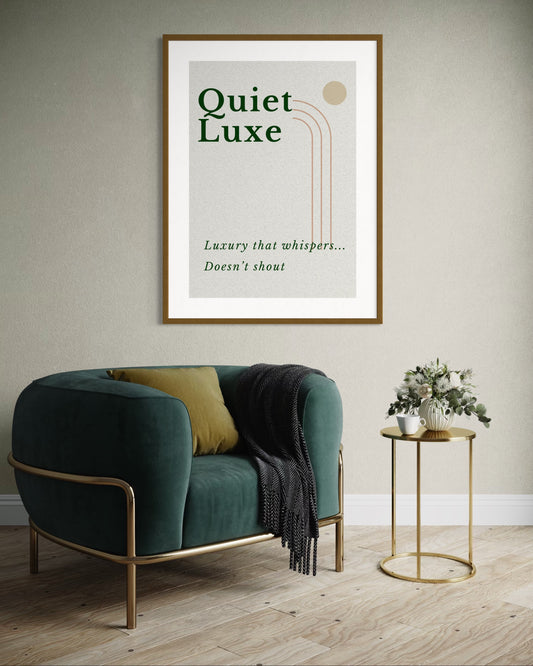 Framed artwork with 'Quiet Luxe' text above a green armchair in a room.