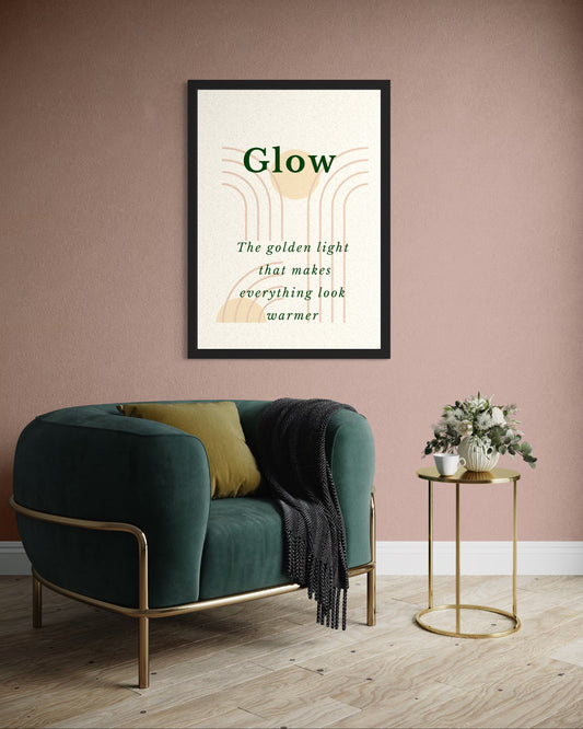Framed artwork titled 'Glow' above a green armchair with a gold side table.