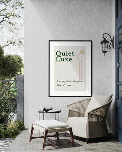 Framed 'Quiet Luxe' poster on a wall with outdoor furniture and garden view.