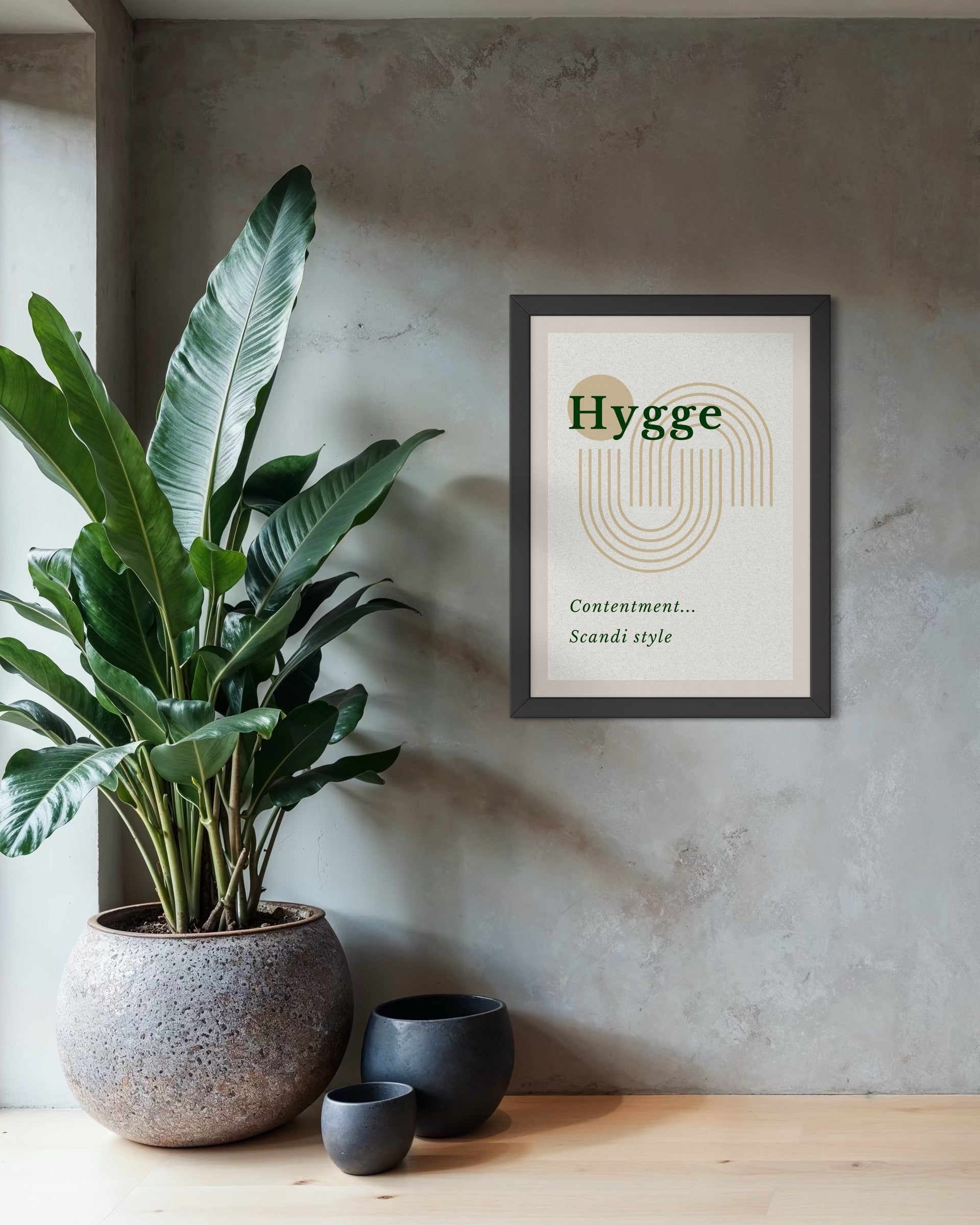 Framed 'Hygge' poster on a wall with a plant and decorative bowls below.