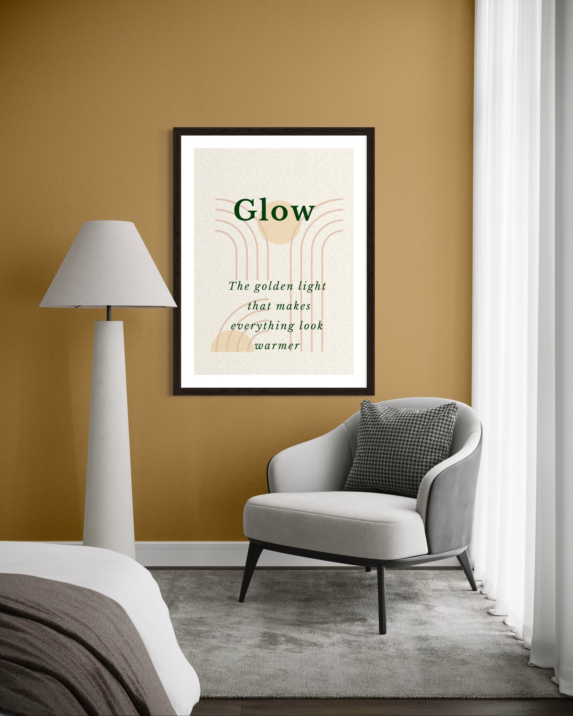 Framed artwork titled 'Glow' on a mustard yellow wall with a gray armchair and white lamp.