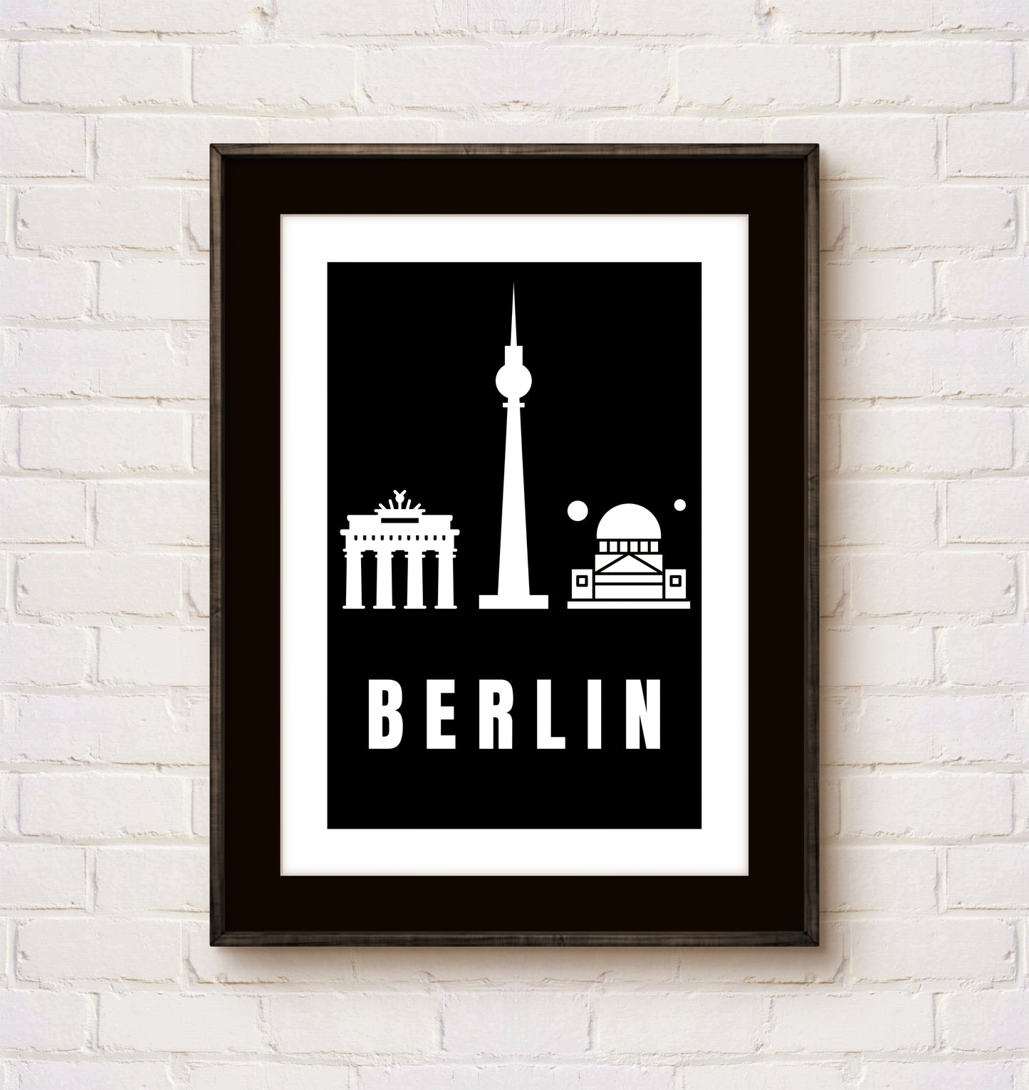 Framed poster with Berlin landmarks on a white brick wall