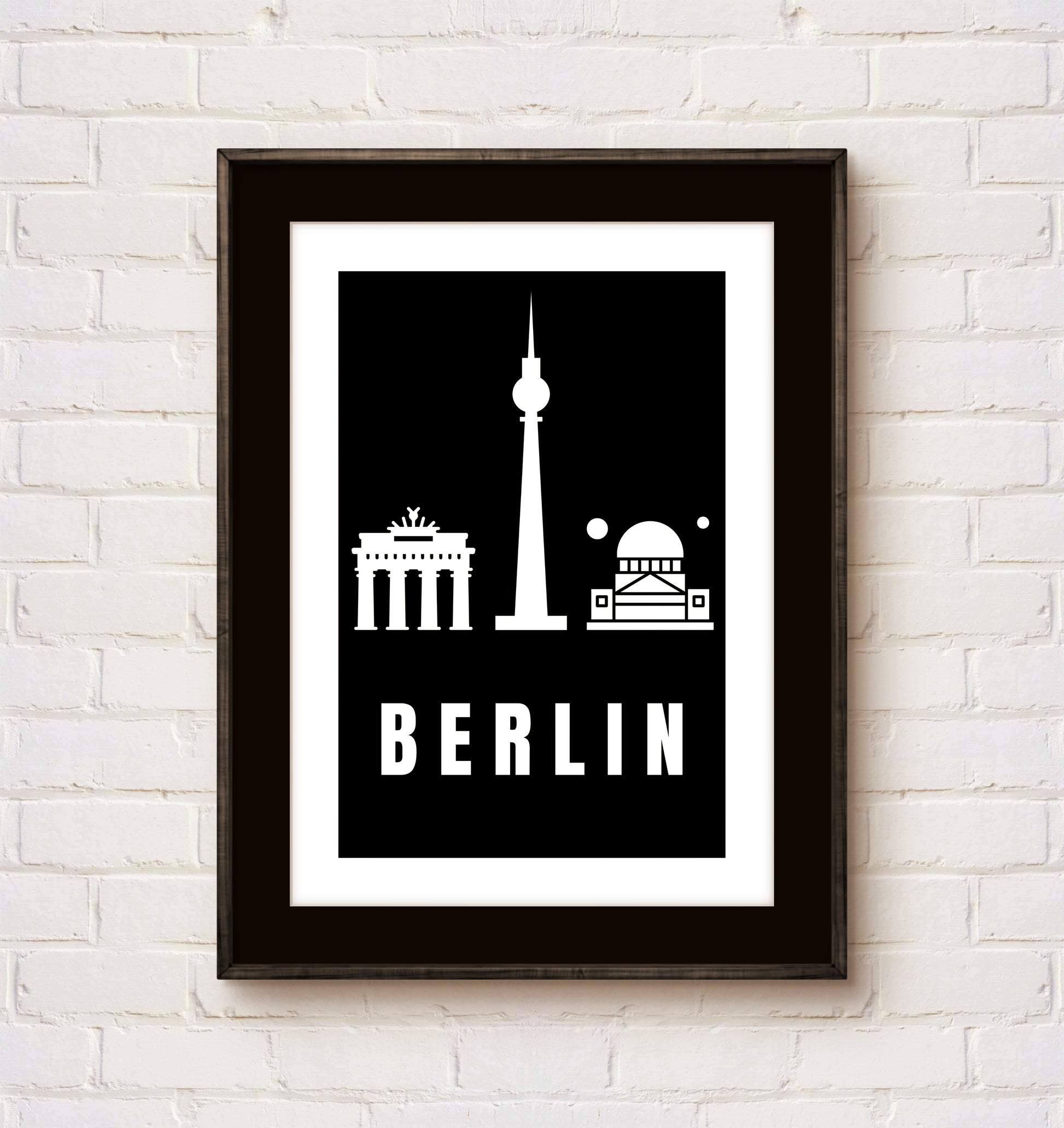 Framed poster with Berlin landmarks on a white brick wall