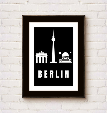 Framed poster with Berlin landmarks on a white brick wall
